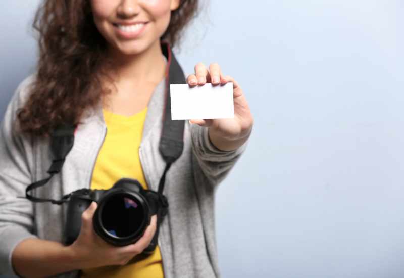 Woman holding a camera and a business card